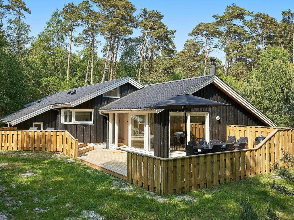 a small cabin with a deck and an umbrella at 8 person holiday home in Nex in Neksø