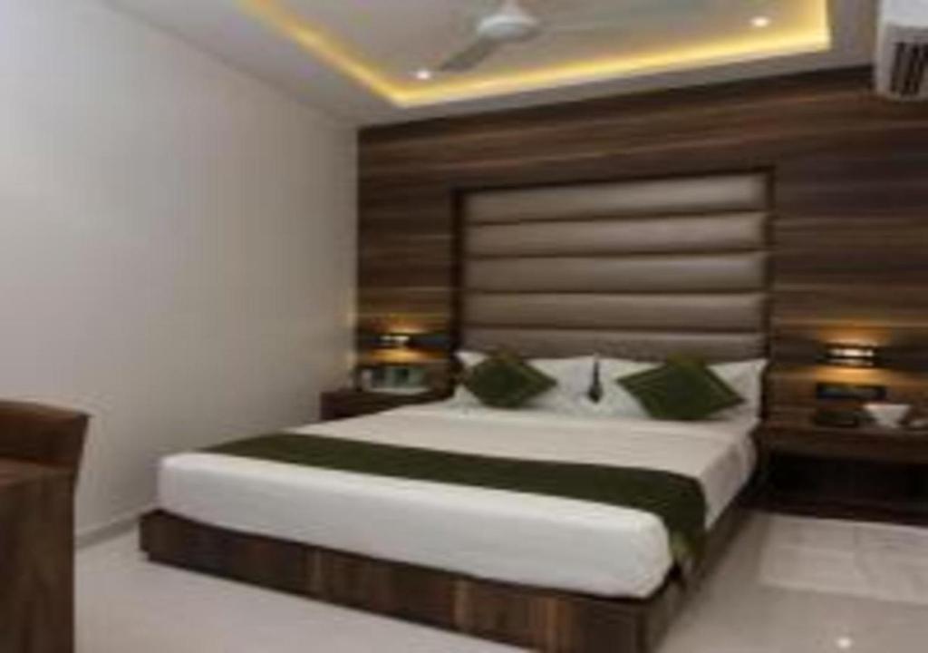 a bedroom with a large white bed with green pillows at Hotel Meriton in Mumbai
