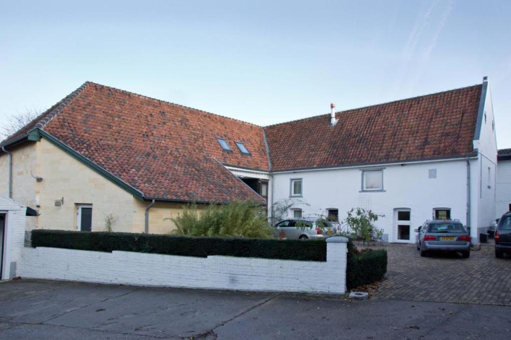 zwei weiße Häuser mit Autos auf einem Parkplatz in der Unterkunft Bed en Breakfast Hof van Wolder in Maastricht