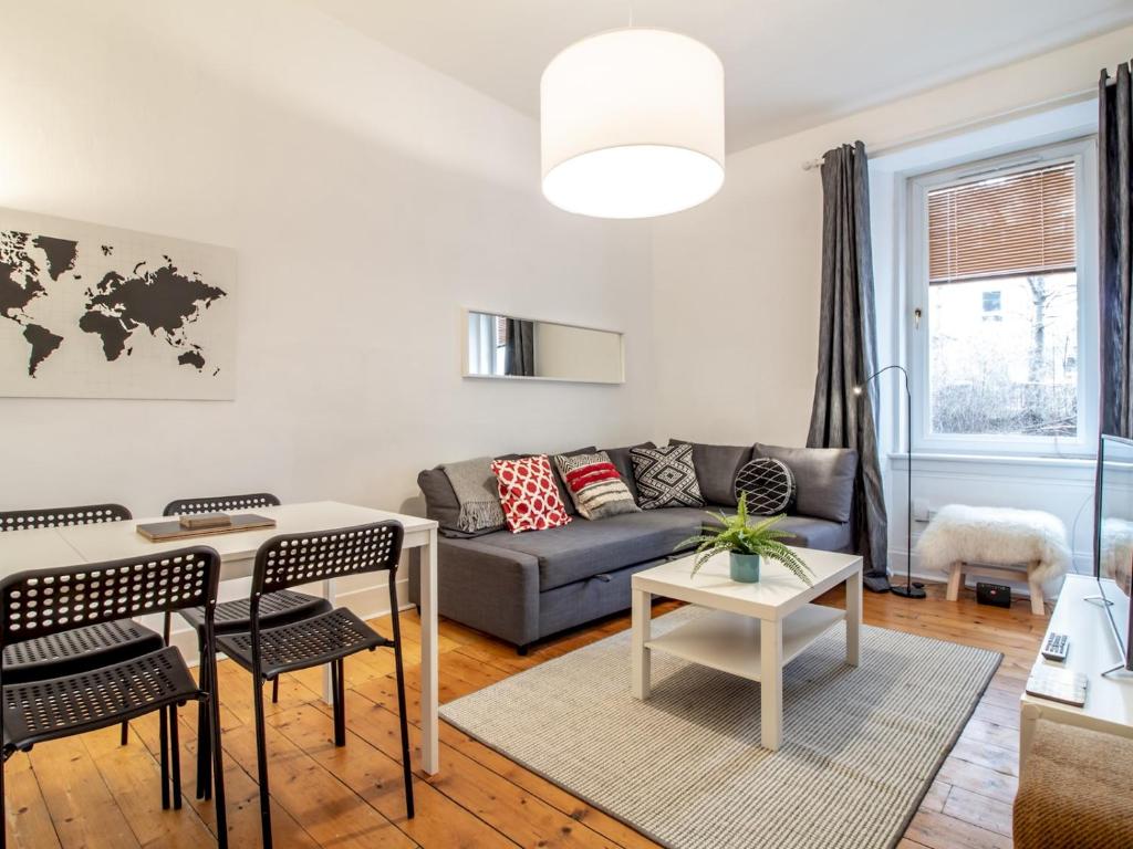 ein Wohnzimmer mit einem Sofa und einem Tisch in der Unterkunft Stylish & Charming Retreat for 2- City Centre! in Edinburgh
