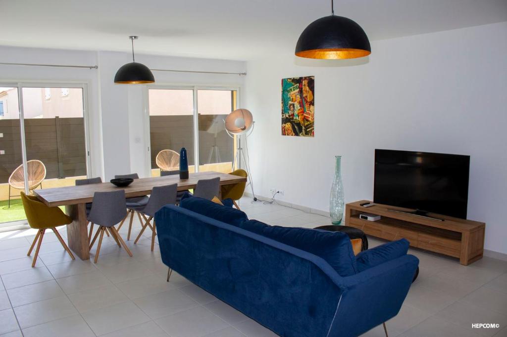 a living room with a blue couch and a dining room table at BASTIDE 7 in La Fare-les-Oliviers