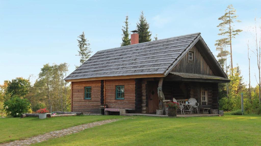 a log cabin with a porch on a grass field at Toidupada puhkemaja in Vidriku Asundus
