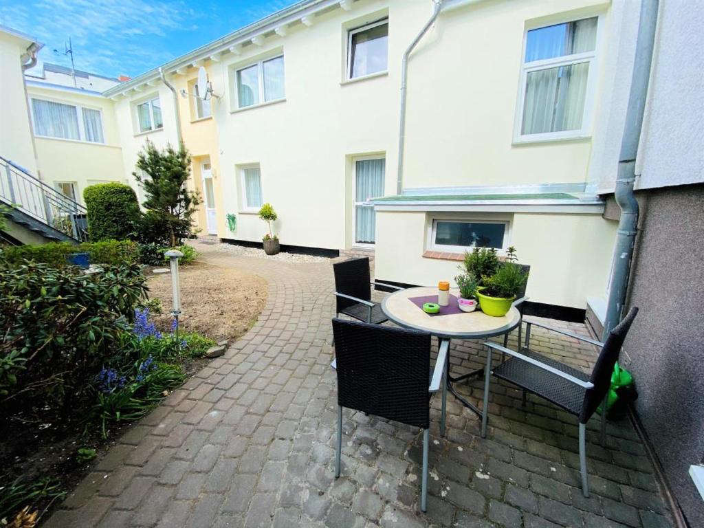 een patio met een tafel en stoelen voor een gebouw bij Appartement Schwalbenflug in Warnemünde