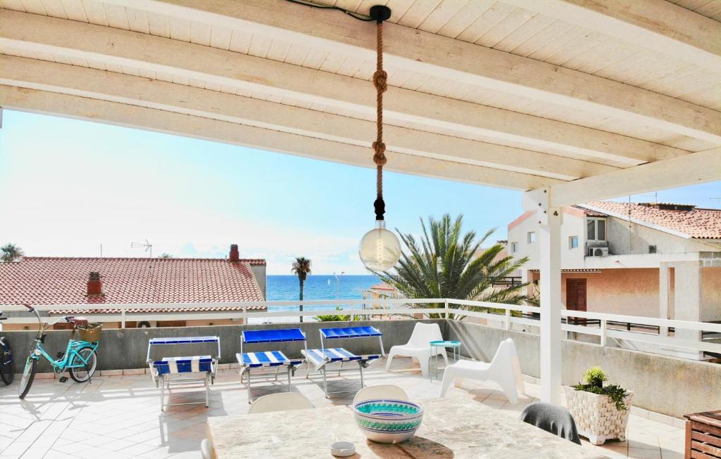 a patio with a table and chairs and a view of the ocean at BeachFront Rooms Marina di Ragusa in Marina di Ragusa