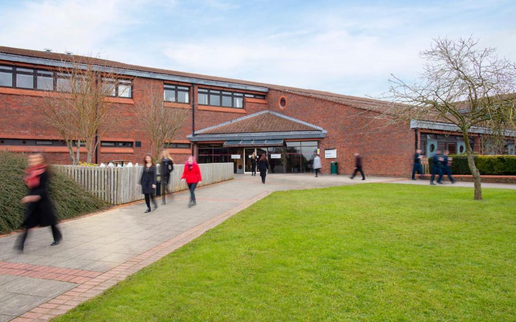 un grupo de personas caminando delante de un edificio en Yarnfield Park Training And Conference Centre, en Stone