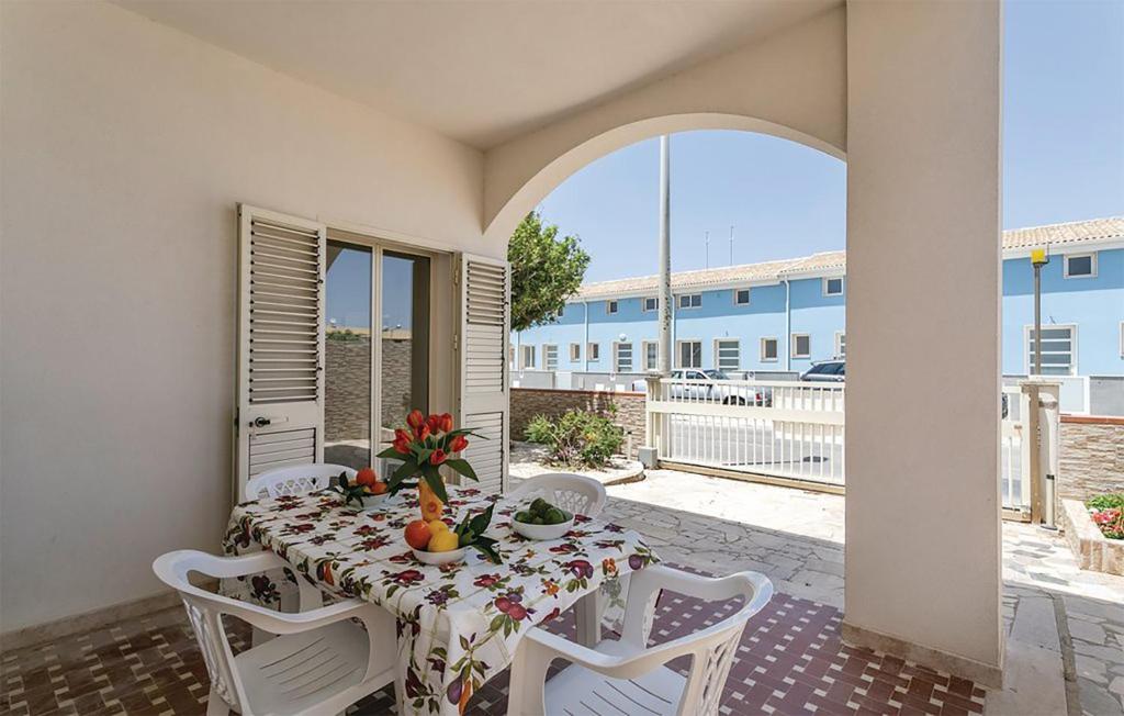 einen Tisch und Stühle auf einer Terrasse mit einem Tisch und einem Fenster in der Unterkunft Villa Rosso Corallo in Punta Secca