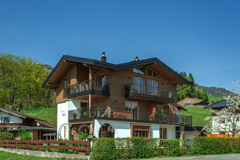 een groot houten huis met balkons op een heuvel bij Ferienhaus Hetzenauer in Kössen
