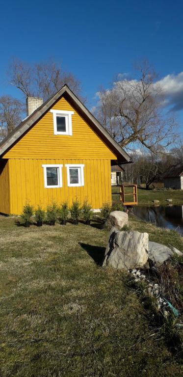 a yellow house in a yard with a rock at Hommik House in Otepää