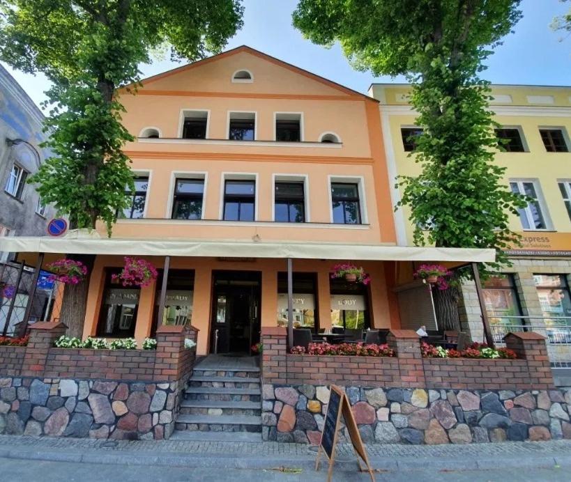 pomarańczowy budynek ze schodami przed nim w obiekcie Kamienica Pod Neptunem w mieście Puck