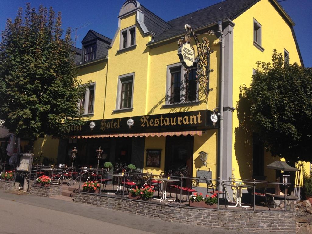 a yellow building with tables and chairs in front of it at Hotel Herres Alte Metzgerei in Leiwen