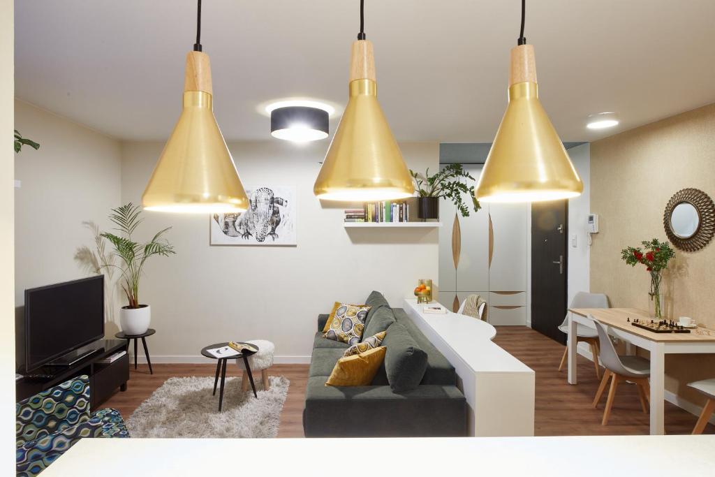 - un salon avec des lampes jaune suspendues et un canapé dans l'établissement Cleopatra Apartment, à Wrocław