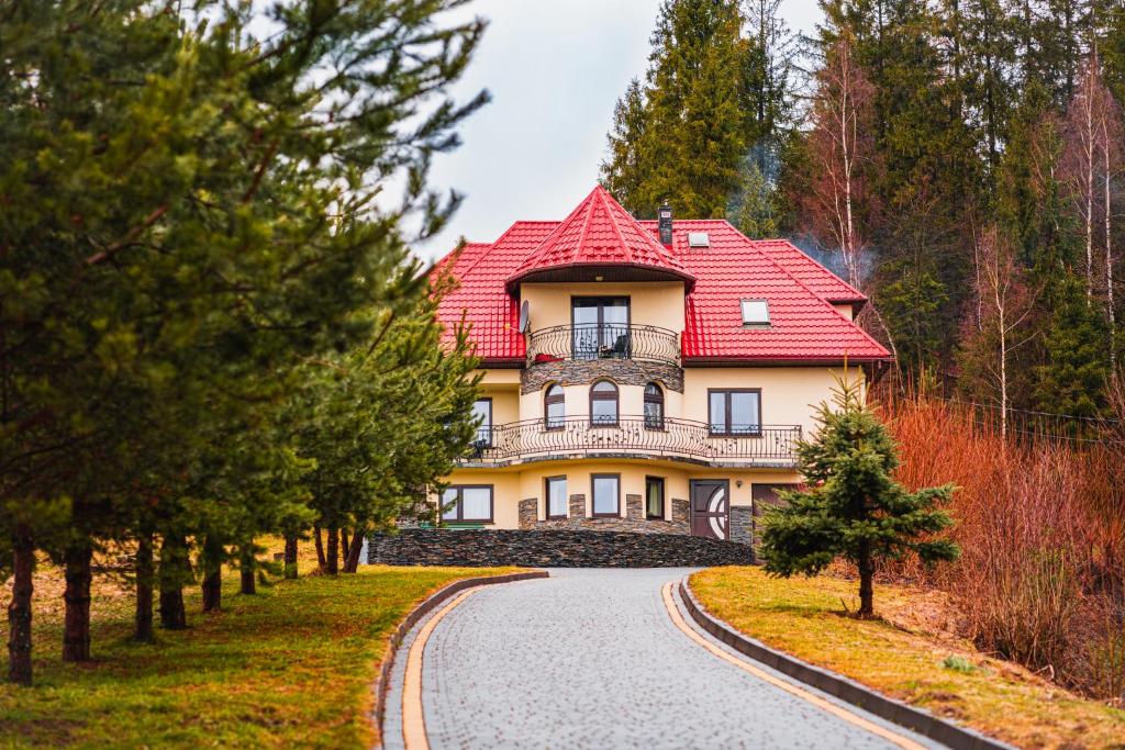 ein großes Haus mit rotem Dach auf einer Straße in der Unterkunft Dom na Turystycznej in PyzÃ³wka