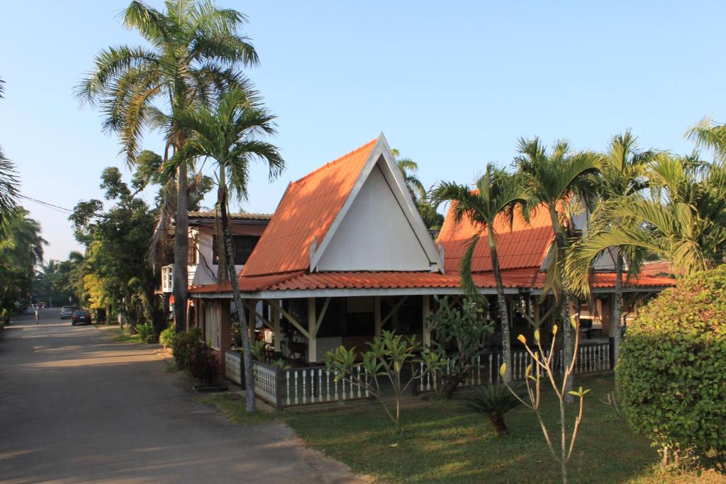 una casa con techo rojo y palmeras en Chaisuk Bungalow en Aranyaprathet