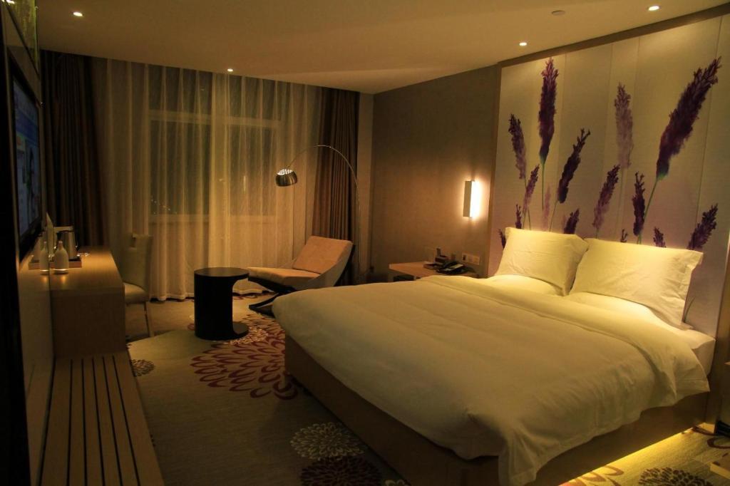 a hotel room with a large bed and a chair at Lavande Hotel Tianshui Gangu Jicheng Square in Tianshui