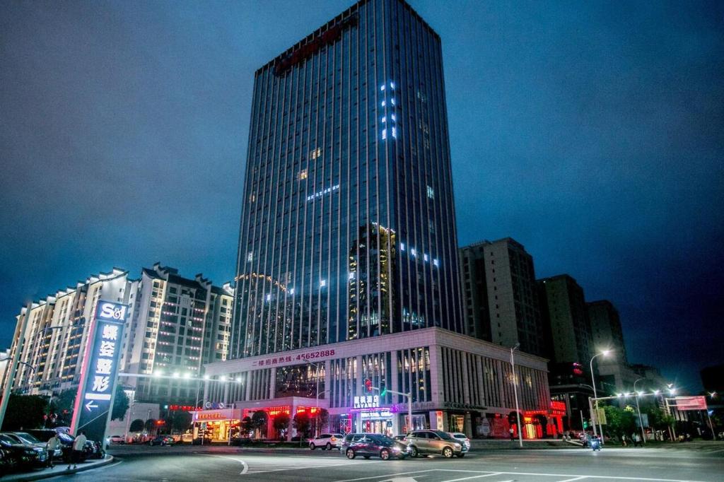 un gratte-ciel haut dans une ville la nuit dans l'établissement Lavande Hotel Chongqing Tongliang Wanda Plaza Gas Tower, à Tongliang