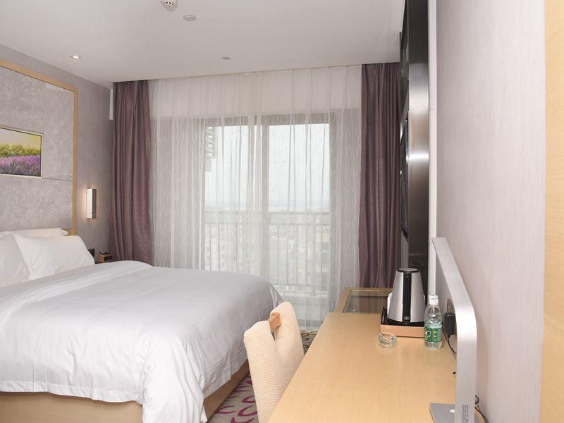 una camera con letto bianco, scrivania e finestra di Lavande Hotel Zhanjiang Xuwen Tianrunhui a Xuwen