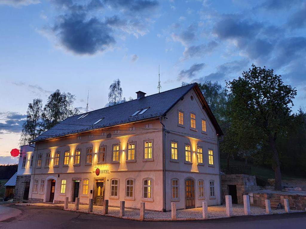 ein großes weißes Gebäude mit eingeschaltetem Licht in der Unterkunft Hotel KORTUS in Jetřichovice