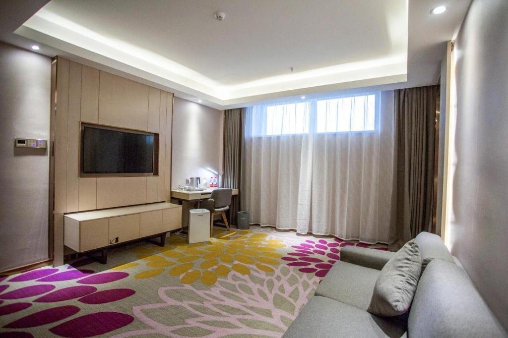 a hotel room with a couch and a tv and a desk at Lavande Hotel Changji Changning Road in Changji