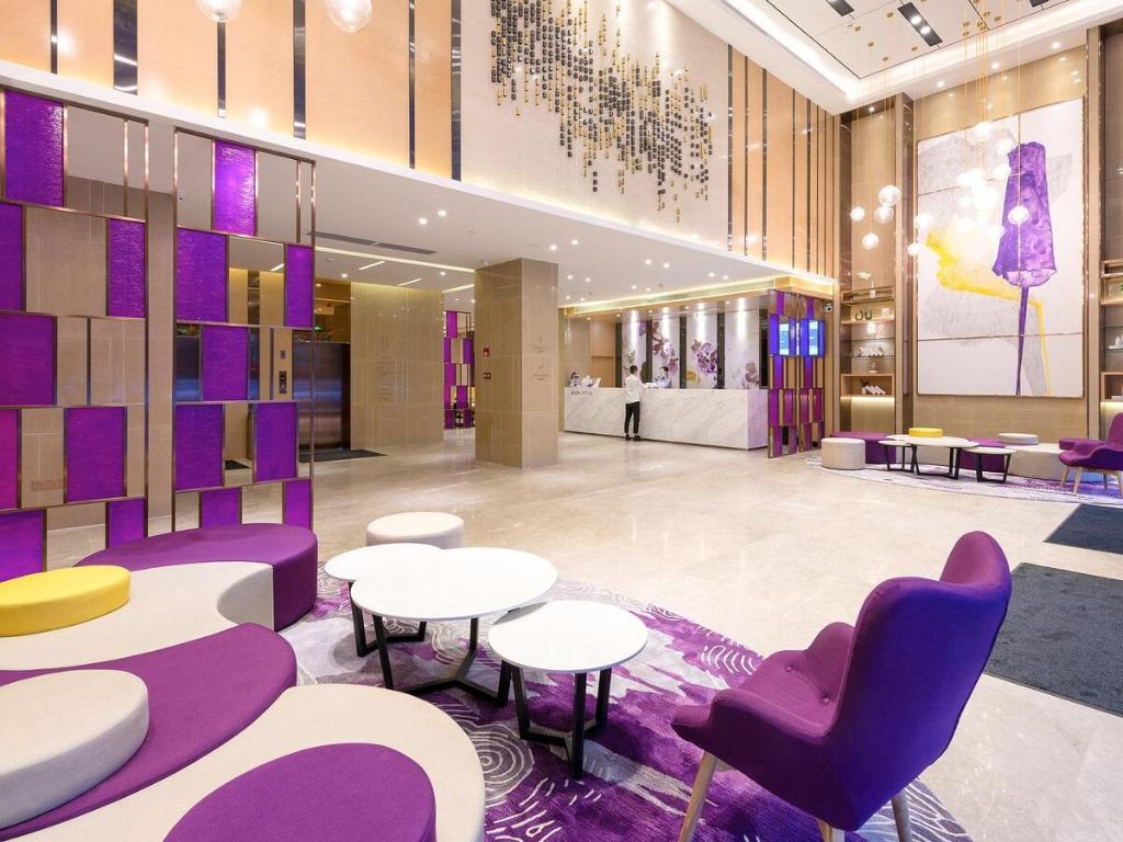 a lobby with tables and chairs and purple chairs at Lavande Hotel Qingyuan Municipal Government New Town Bus Station in Qingyuan