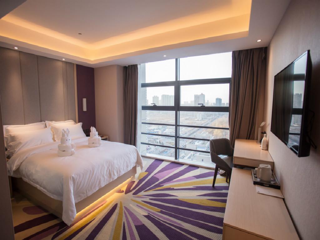 a hotel room with a bed and a large window at Lavande Hotel Korla city government swan lake in Korla