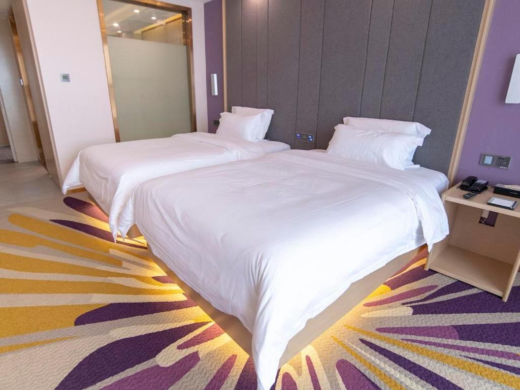2 Betten in einem Hotelzimmer mit weißer Bettwäsche in der Unterkunft Lavande Hotel Bazhong Fortune Center in Bazhong