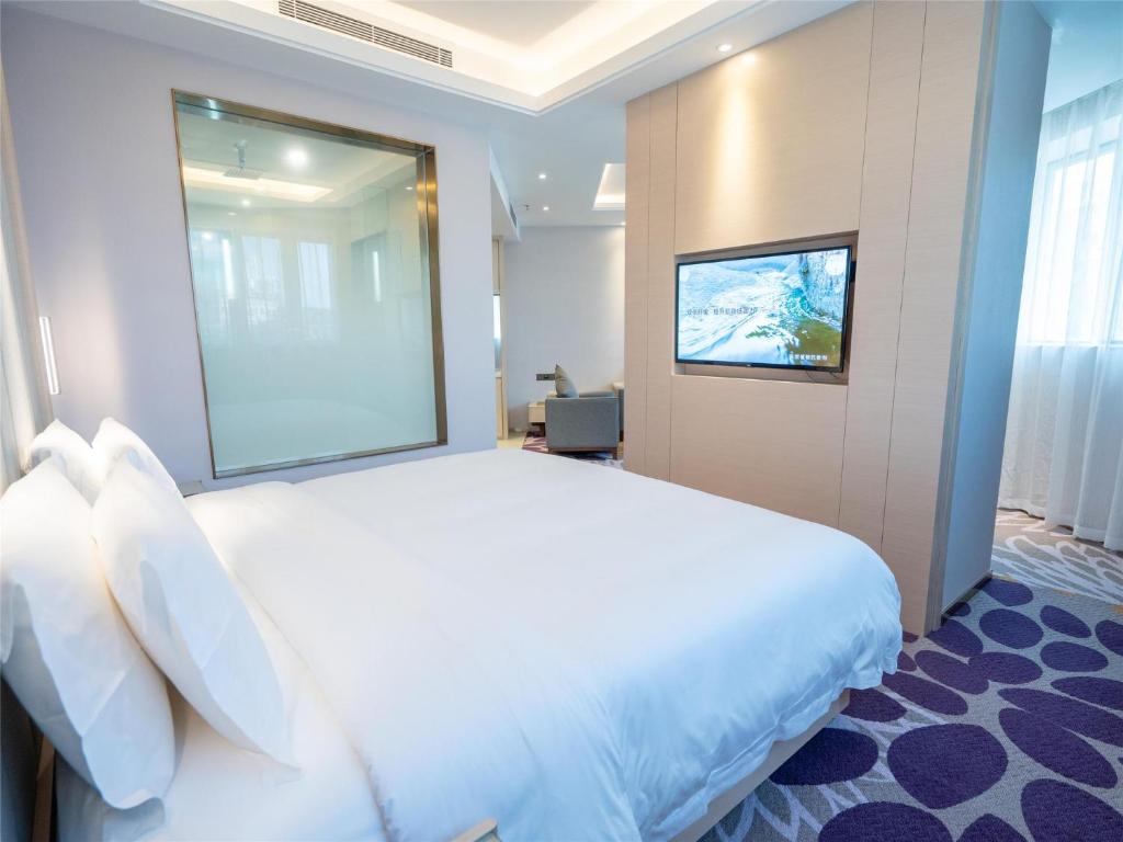 a hotel room with a large bed and a television at Lavande Hotel Zhongshan Tanzhou in Zhongshan