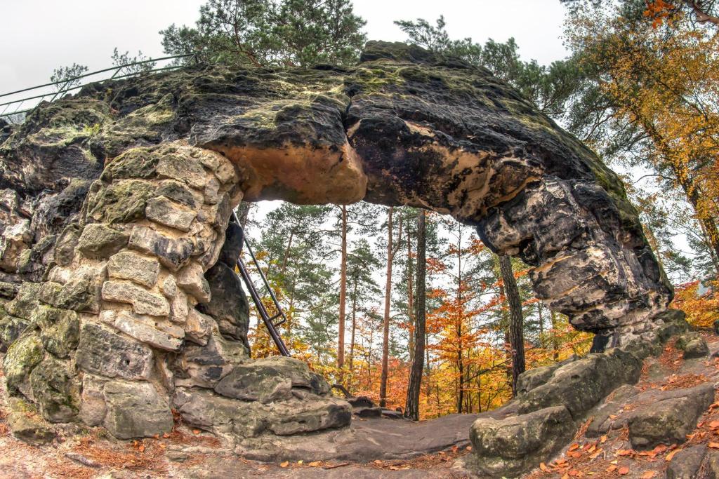 a stone archway in the middle of a forest at Hotel KORTUS in Jetřichovice