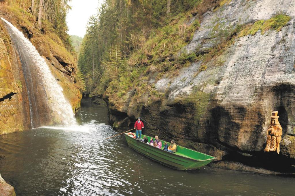 a group of people in a boat in front of a waterfall at Hotel KORTUS in Jetřichovice
