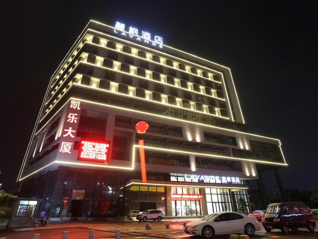 a hotel building with neon signs at night at Lavande Hotel Dongguan Liaobu Center in Dongguan
