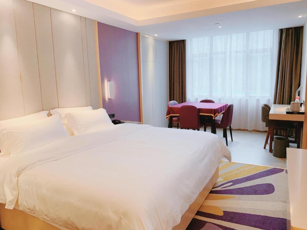 a hotel room with a large bed and a table at Lavande Hotel Huizhou Xinxu Government Square in Niu'ao
