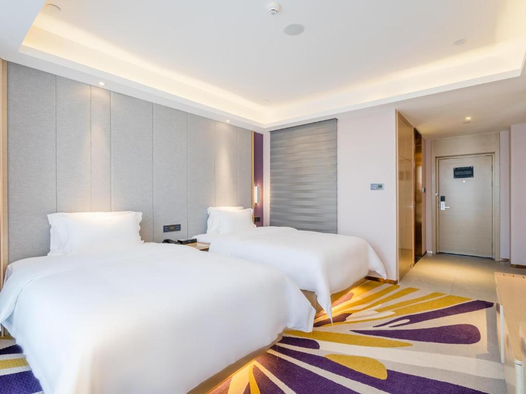 a hotel room with two beds and a hallway at Lavande Hotel Luzhou Wanda Plaza Southwest Commercial City in Luzhou