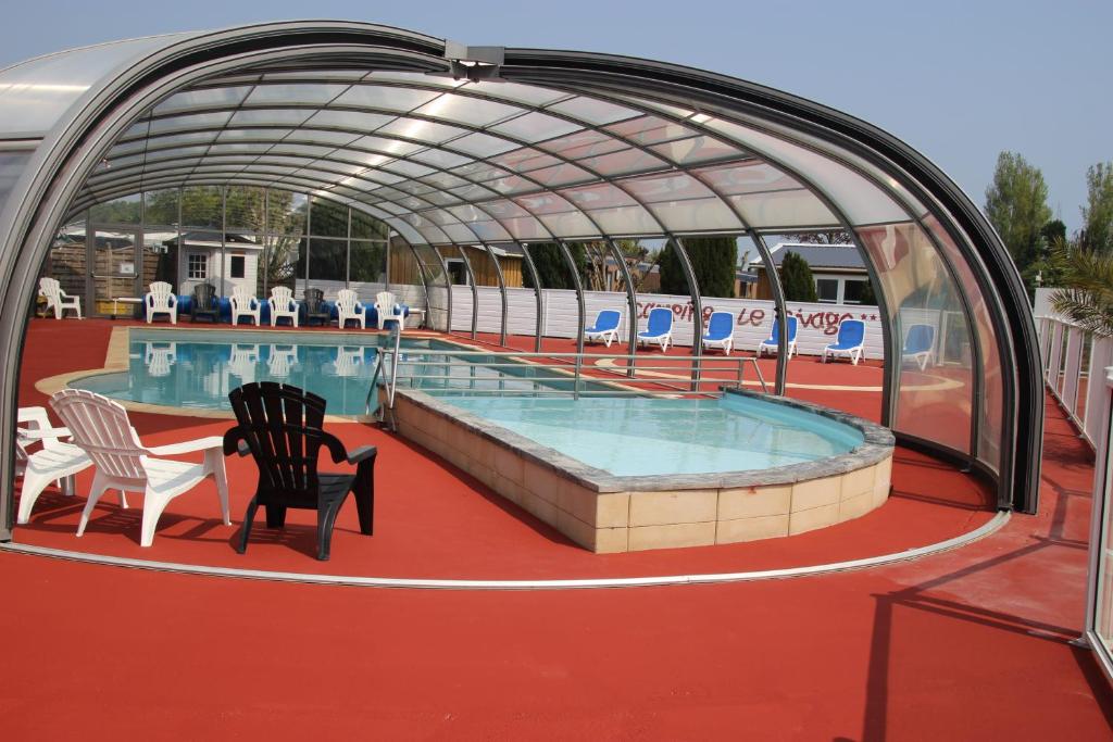 a pool on a cruise ship with two chairs and a table at Camping le Rivage in Quettehou
