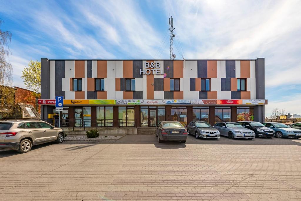 een gebouw met auto's geparkeerd op een parkeerplaats bij Air Kaunas in Karmėlava