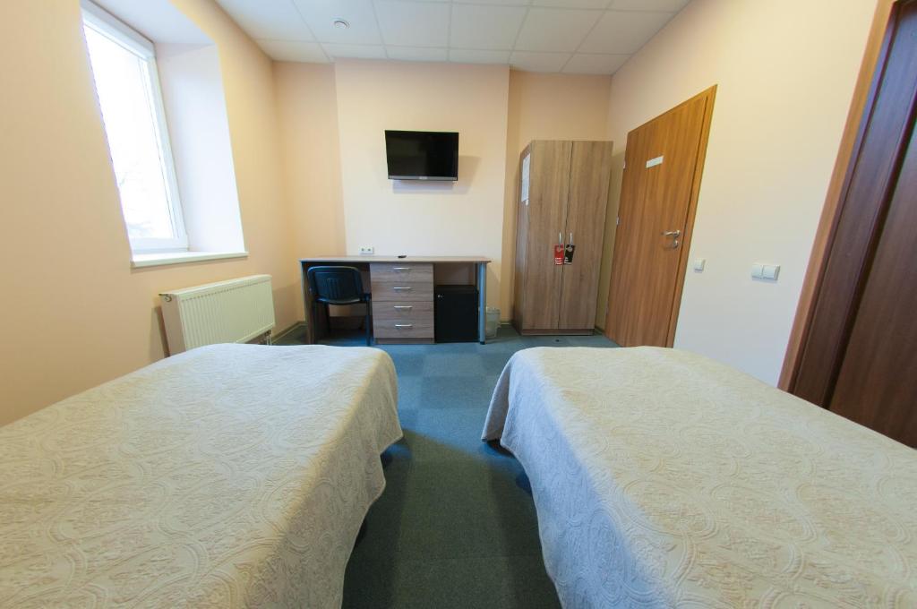 a hotel room with two beds and a desk at Air Kaunas in Karmėlava