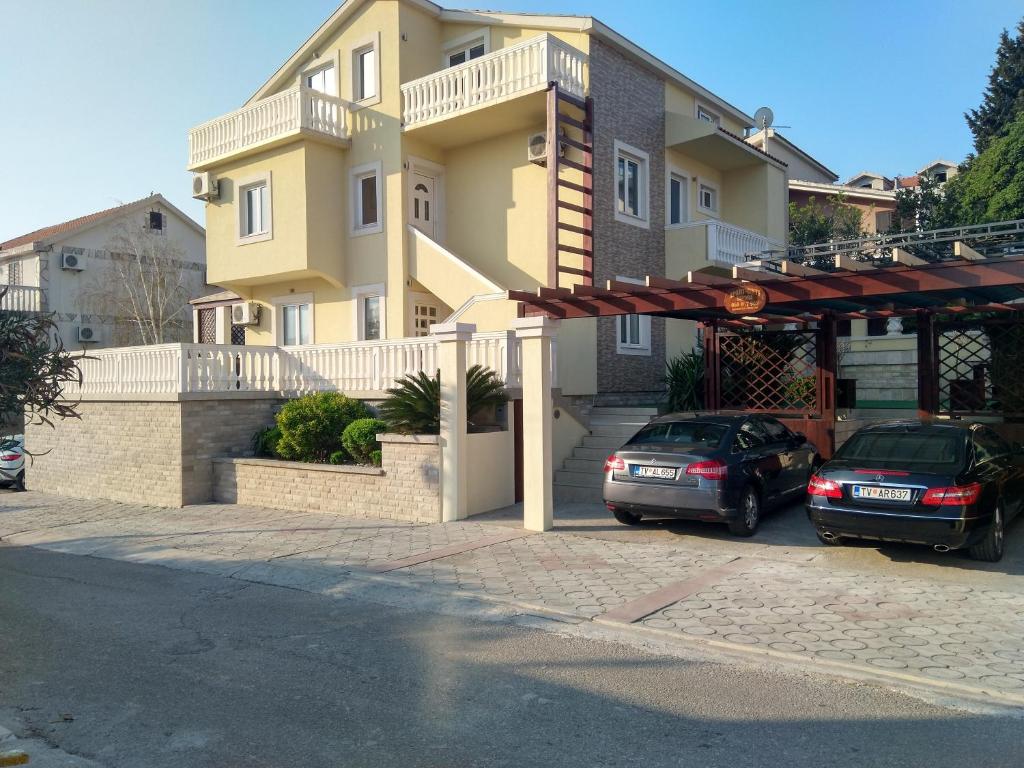 dwa samochody zaparkowane przed budynkiem w obiekcie Apartments Sandra w mieście Tivat