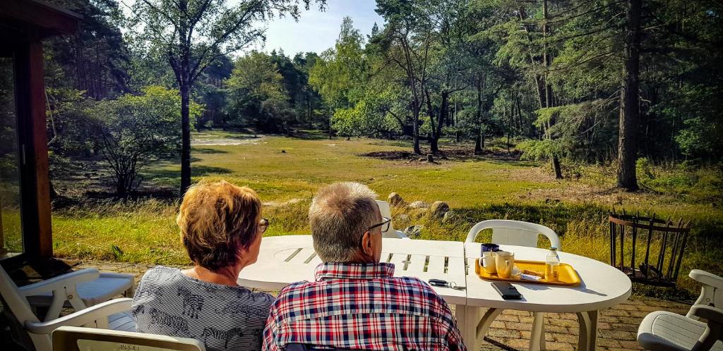 una pareja mayor sentada en una mesa mirando un campo en Vakantiehuis de Weeser Enk en Epe