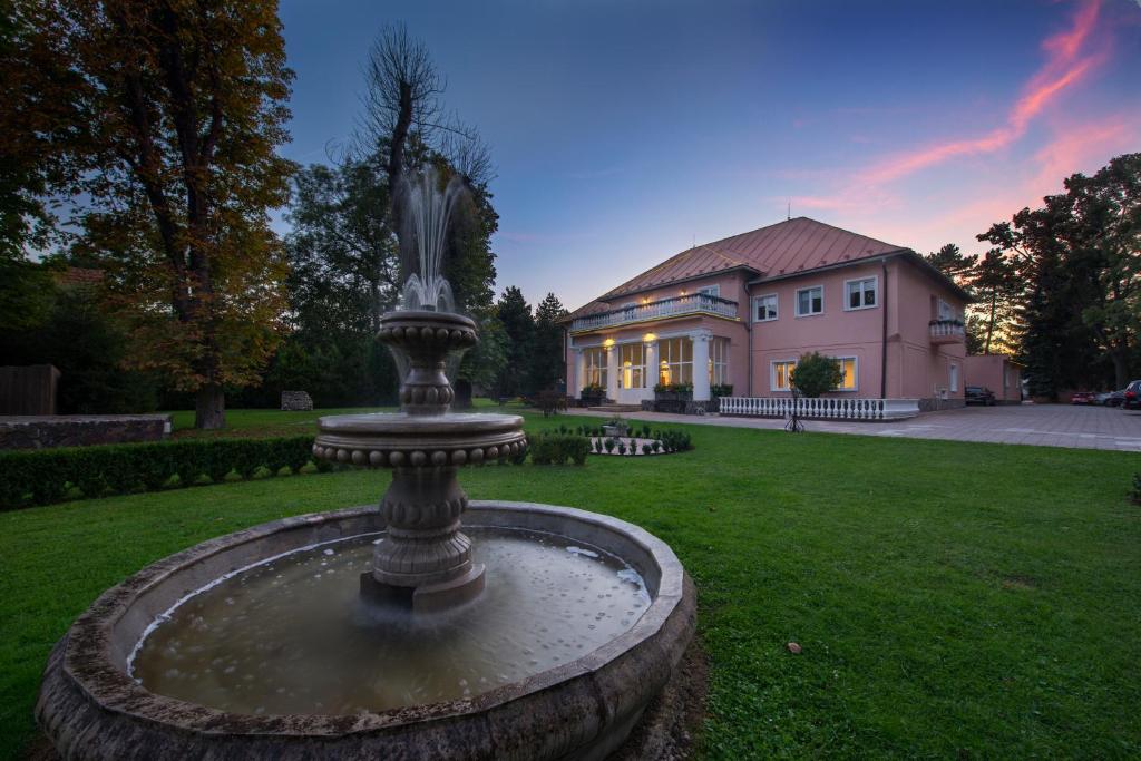 una fuente frente a una casa grande en Svatojansky Kastiel, en Liptovský Ján