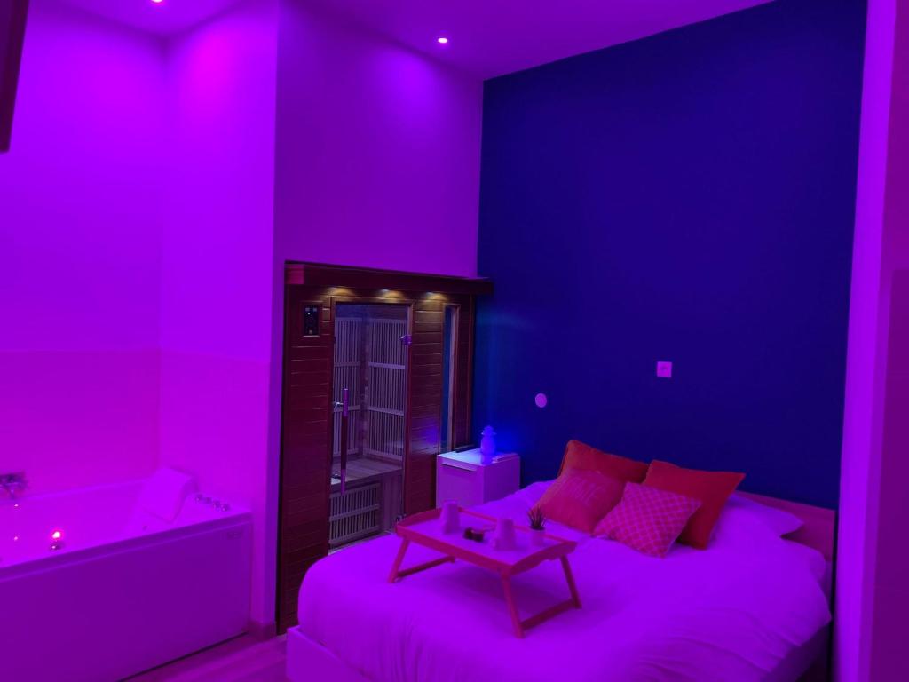 Habitación púrpura con cama y bañera en Appartement Spa - NAHLEO Scandinave en Dole