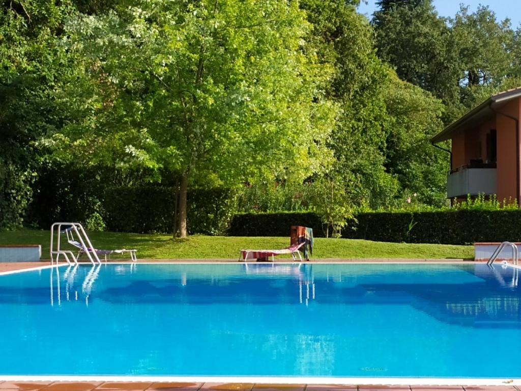 een groot blauw zwembad met een boom op de achtergrond bij Rosalinde House in Colà di Lazise