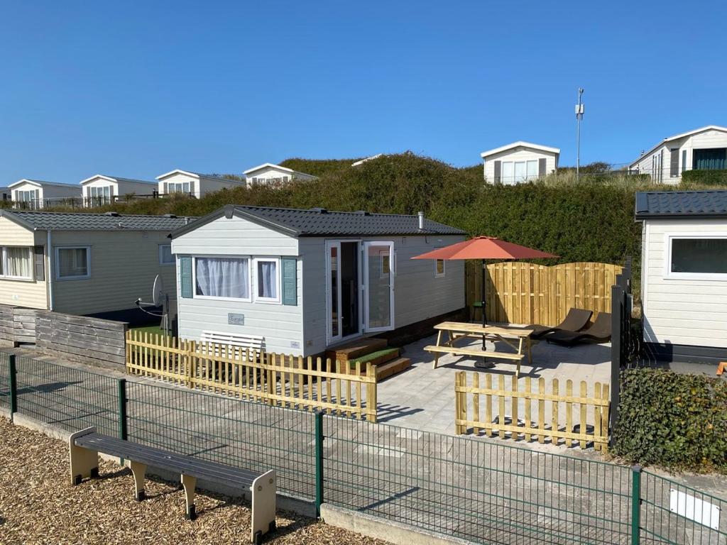 a view of a backyard with a house and a picnic table at Luxe Chalet op camping Duindoorn, IJmuiden aan Zee, in de buurt van F1 circuit Zandvoort en Bloemendaal op loopafstand strand in IJmuiden