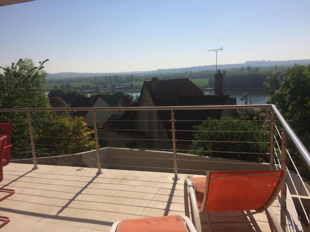 a balcony with two chairs and a view of a river at Appartement avec grande terrasse pour 6 personnes in Athis-Mons