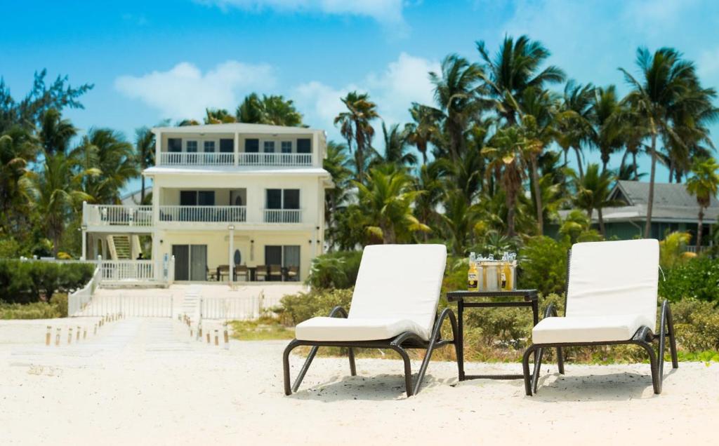 two chairs and a table on the beach in front of a house at Villa Turkuaz in Providenciales