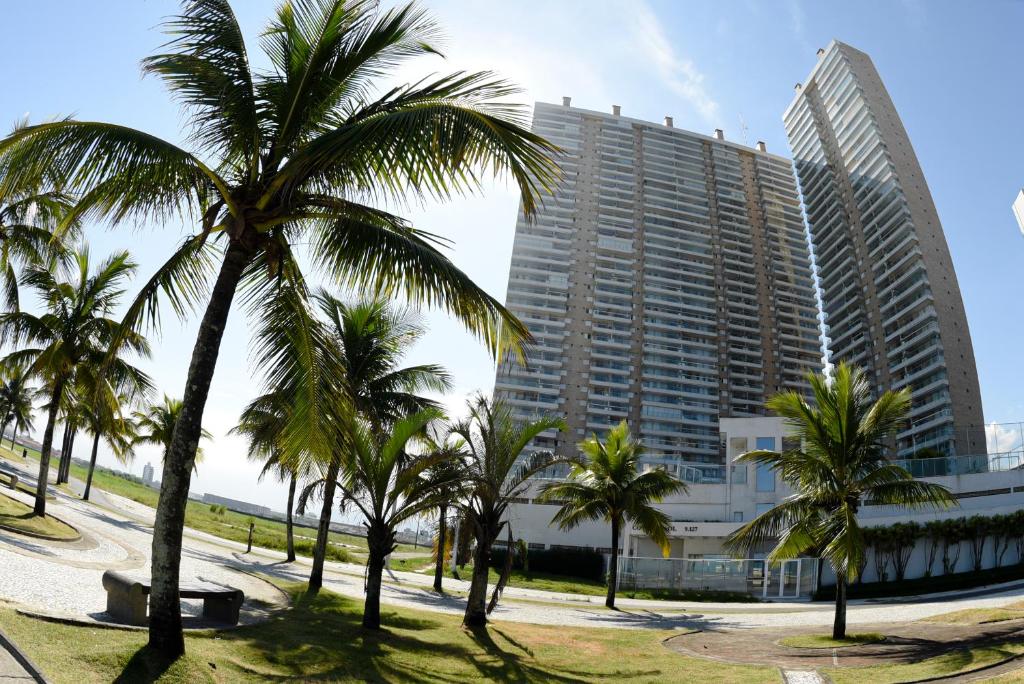un edificio alto con palmeras delante en Costa do Sol, en Praia Grande