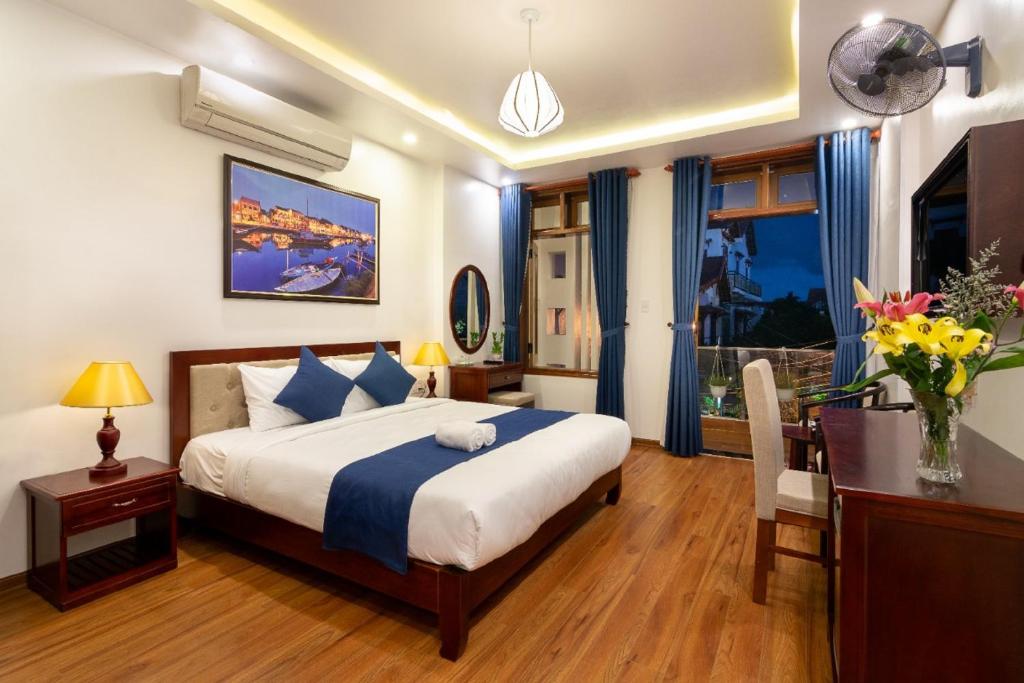 een slaapkamer met een bed, een bureau en een televisie bij The Linh Hoi An Villa in Hội An