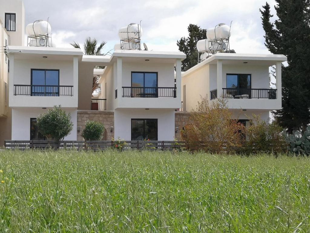 a large white building with windows and a grass field at Seashell Apartments in Paphos