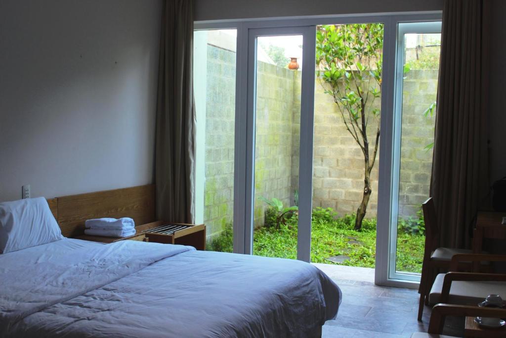 a bedroom with a bed and a sliding glass door at Jolie Villa Hoi An in Hoi An