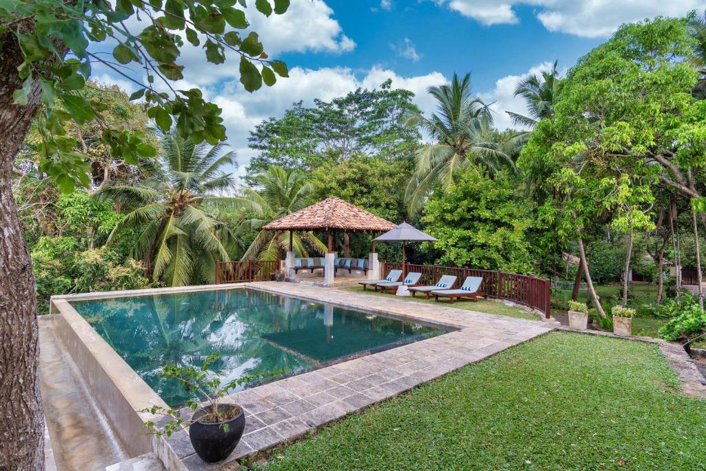 een achtertuin met een zwembad en een prieel bij Villa Karamoja in Koggala