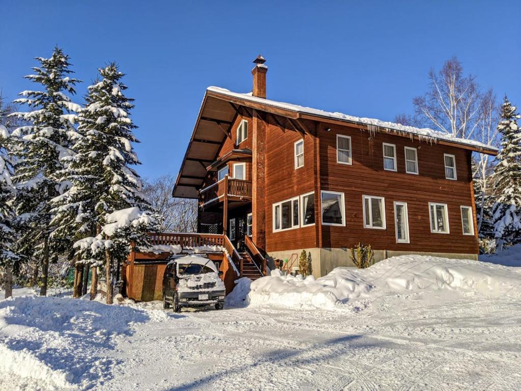 uma casa na neve com um camião estacionado em frente em Niseko Ski Lodge - Higashiyama em Niseko