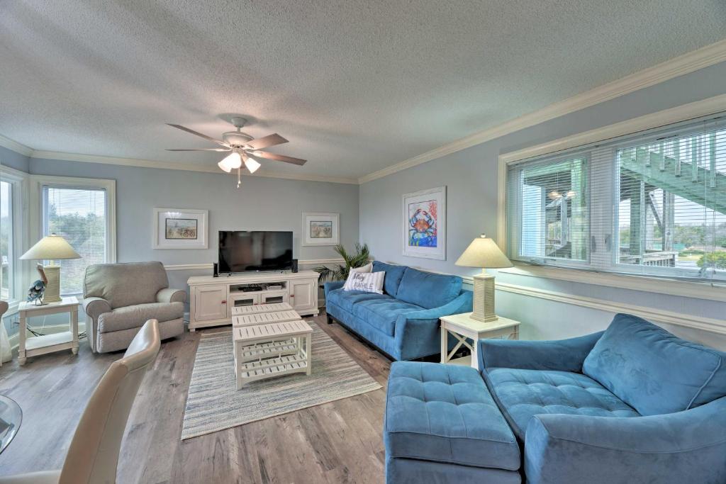 a living room with blue couches and a tv at Bright Emerald Isle Condo with Private Beach Access! in Emerald Isle