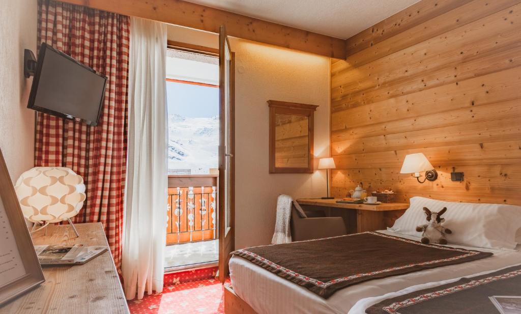 a hotel room with a bed and a desk and a window at Hôtel Le Sherpa Val Thorens in Val Thorens